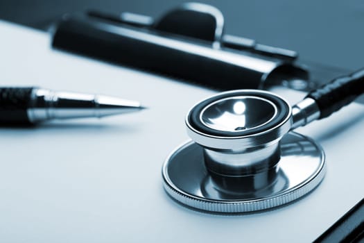 Closeup of medical stethoscope on clipboard. Toned in blue