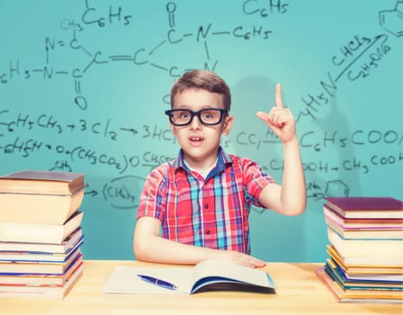 Scientist little boy gets knowledge in the school library. Pupil in glasses against books