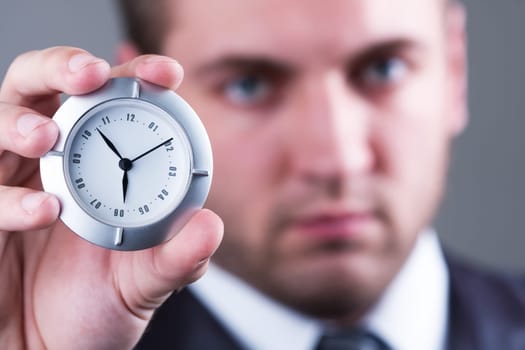 Adult serious businessman shows a little white clock
