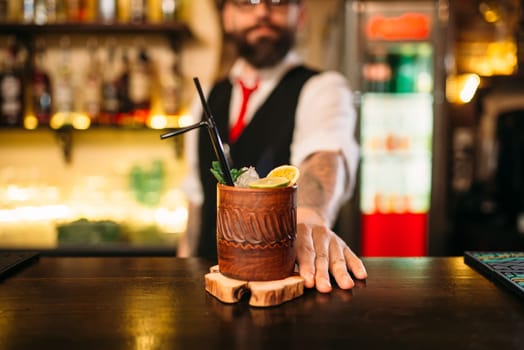 Barkeeper shows attractive alcoholic cocktail. Handsome alcohol beverage preparation