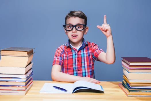 Little schoolboy learns homework at the desk in classroom. Pupil in glasses gets knowledge