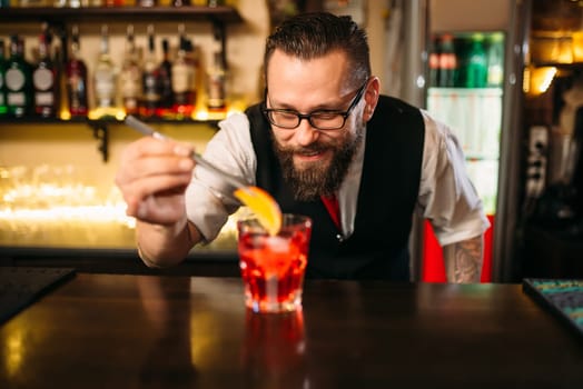 Bartender behind bar counter making alcohol coctail in restaurant