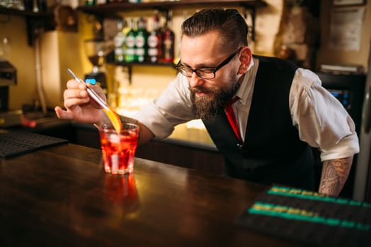 Bartender behind bar counter making alcohol coctail in restaurant