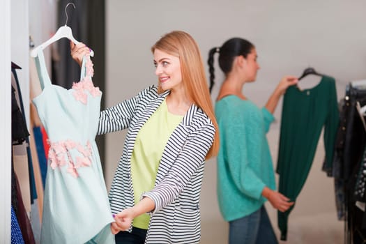 Two women shopping, one is excited holding a cute dress
