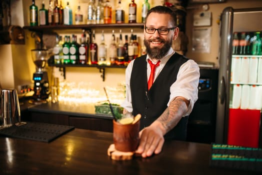Barkeeper shows attractive alcoholic cocktail. Handsome alcohol beverage preparation
