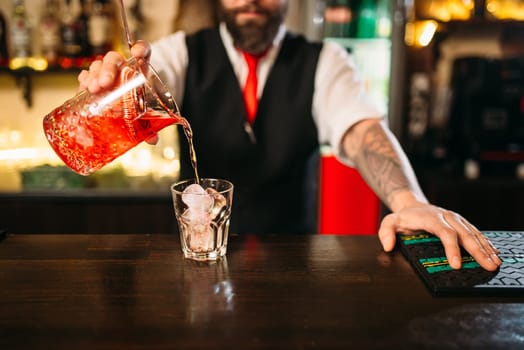 Barman pouring alcoholic drink in glass. Bartender flairing in restaurant