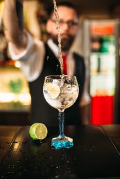 Bartender pouring alcoholic drink in glass. Barman flairing with alcoholic cocktail