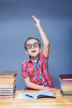 Little pupil pulls a hand up at the lesson in classroom. Education concept