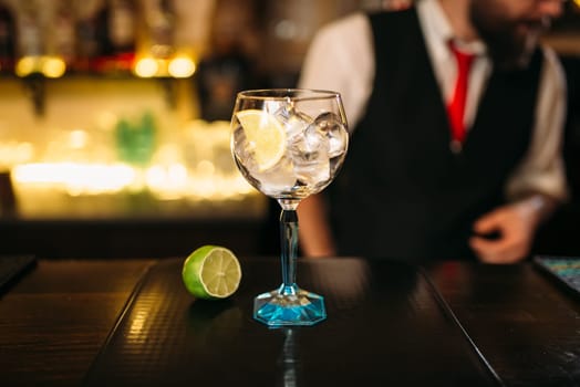 Attractive cocktail and lime on wooden counter. Advertising of alcoholic beverages
