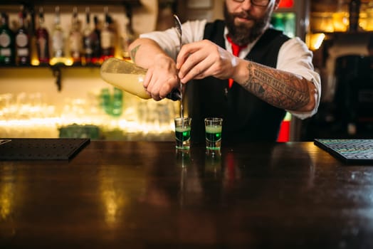 Barkeeper pouring alcoholic beverage in glass behind restaurant bar counter