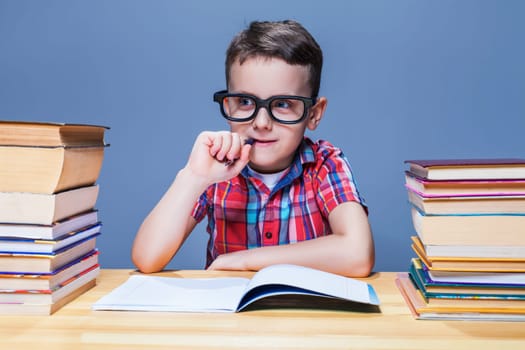 Pensive schoolboy study at school, homework learning. Pupil in glasses against books