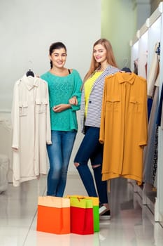Happy smiling women holding dresses in the shop