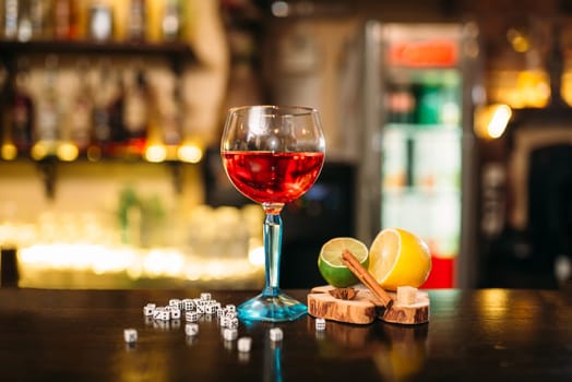 Beverage in glass, lime, lemon, salt and dice on wooden bar counter
