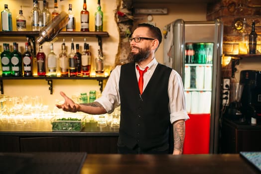 Bartender with shaker show trick behind a bar counter. Modern club nightlife