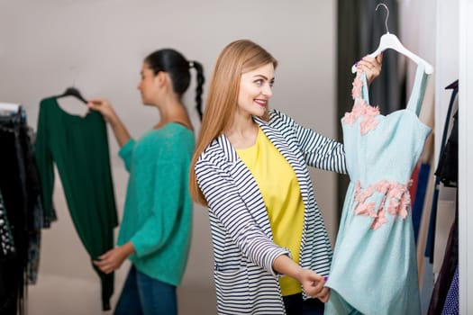 Two young women buyinng dresses in the shop