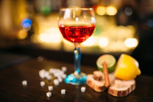 Beverage in glass, lime, lemon, salt and dice on wooden bar counter