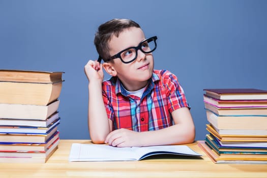 Pensive schoolboy study at school, homework learning. Pupil in glasses against books