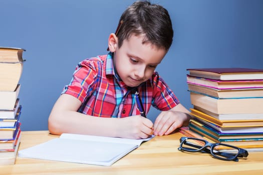 Pensive schoolboy study at school, homework learning. Pupil in glasses against books