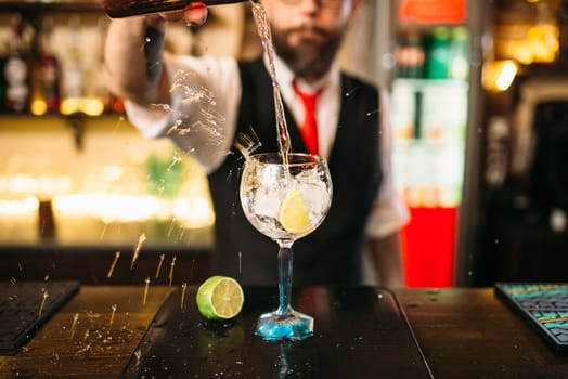 Bartender pouring alcoholic drink in glass. Barman flairing with alcoholic cocktail