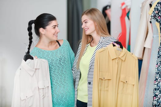 Happy smiling women holding dresses in the shop