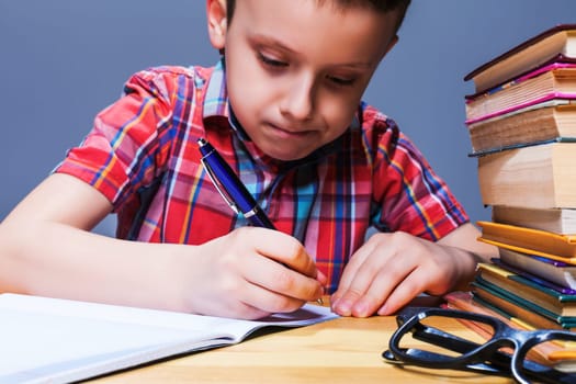 Little child writing in notebook, school homework concept. Young pupil at the desk in classroom