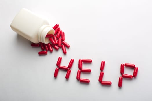 Pills spilling from an open bottle in HELP word