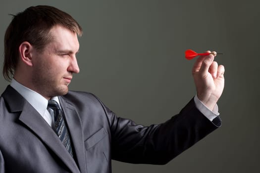 Business games - young businessman aiming by dart