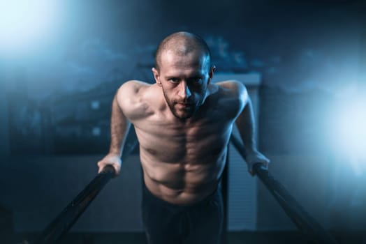 Muscle gymnast exercises on sports bars in gym. Strong athlete on gymnastic training