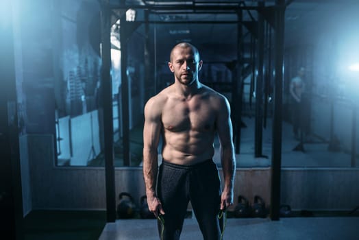 Portrait of strong athlete with jump rope in hands on workout. Sportsman on fitness training in gym. Active sport lifestyle