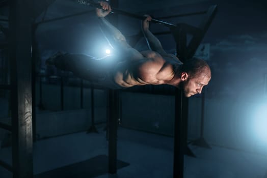 Healthy athlete with muscular body making efforts to keeps the horizontal balance. Strong man on workout