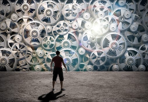 Silhouette of man standing against background of gears and cogwheels