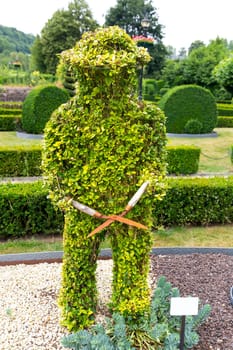 Figure in shape of lawn mower from the bushes, summer park in Europe. Professional gardening, european green landscape, garden plants decoration