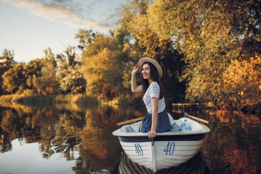 Pretty lady poses in boat on quiet lake at summer day. Romantic date, boating trip, man and woman walking along the river