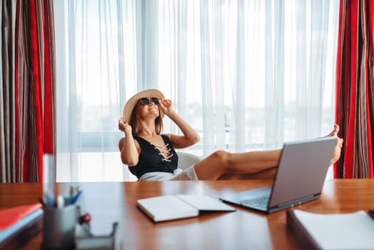 Young businesswoman sitting at the table in the office and dreaming about a vacation