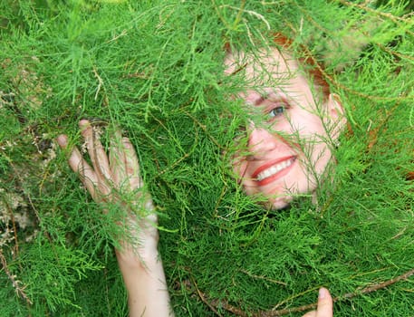 Young smiling woman in thuja tree