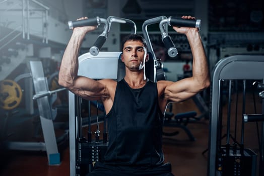 Tanned man training on exercise machine. Active sport workout in gym