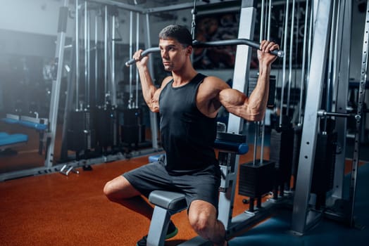 Tanned athlete workout on exercise machine in gym. Active training in sport club
