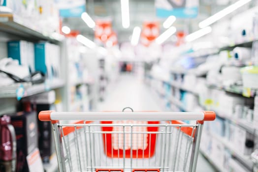 Empty cart in department of household appliances, supermarket. Trolley in market, nobody
