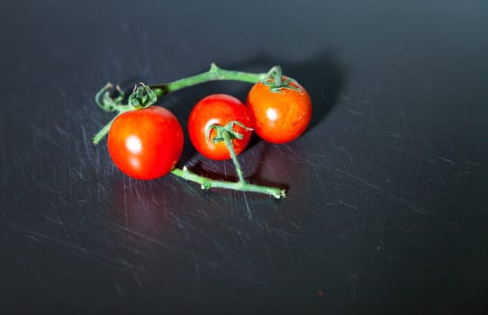 Branch of fresh red cherry tomatoes isolated on the board