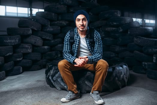 Stalker, alone traveler against mountain of tires, abandoned factory. Danger zone, deserted place