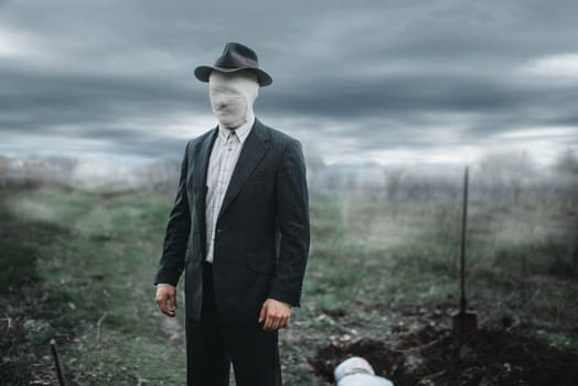 Serial murderer with face wrapped in bandages against grave with victim, bloody maniac concept, crazy monster, crime and violence
