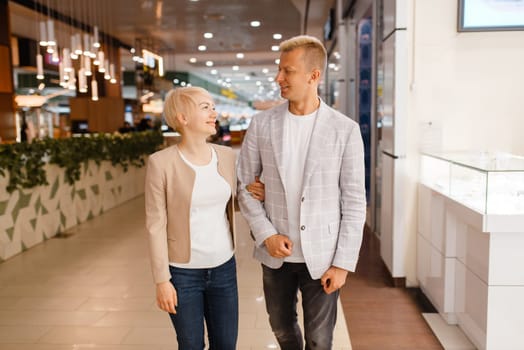 Happy love couple at the jewellery shop. Male and female consumers buying jewels in jewelry store. Man and woman purchase gold decorations