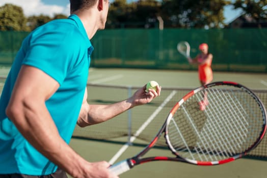 Male and female players with rackets on outdoor tennis court. Summer season active sport game