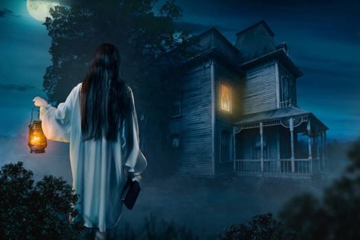 Female person in white shirt holds kerosene lamp and spellbook in hand against abondoned house, moonlit night, back view. Dark magic, occultism and exorcism