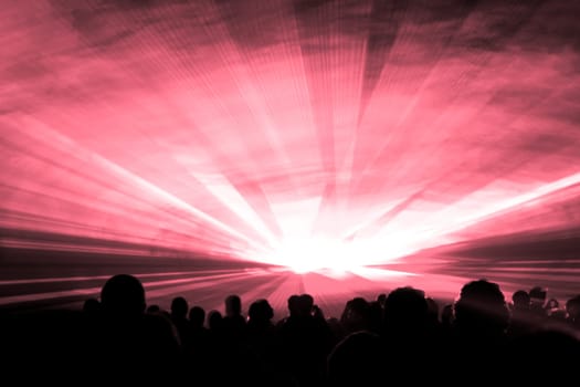 Luxury entertainment with audience silhouettes in nightclub event, festival or New Years Eve. Beams and rays shining colorful lights.