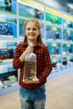 Happy little girl holds goldfish and makes a wish, pet store. Child buying equipment in petshop, accessories for domestic animals