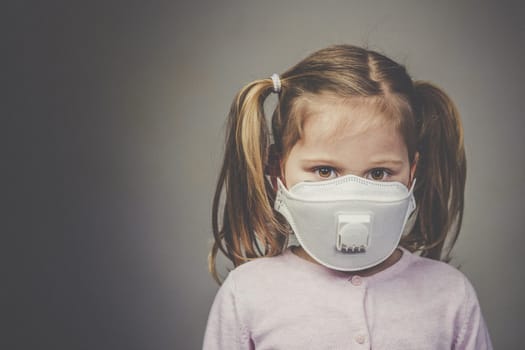 portrait of a girl with pigtails wearing a medical mask to protect herself from the crown virus infection.