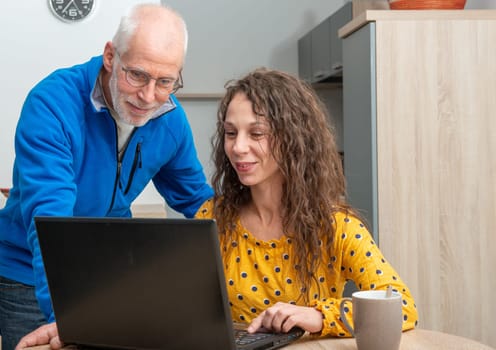 Young woman helps senior on a laptop computer