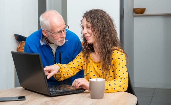 Young woman helps senior on a laptop computer