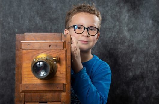 cheerful boy retro photographer with a vintage wooden camera